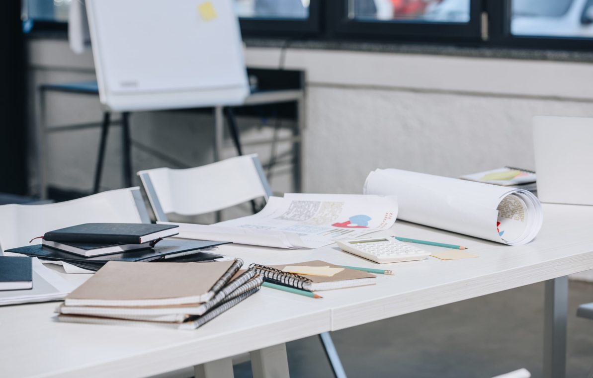 documents, notebooks and blueprints on table in office